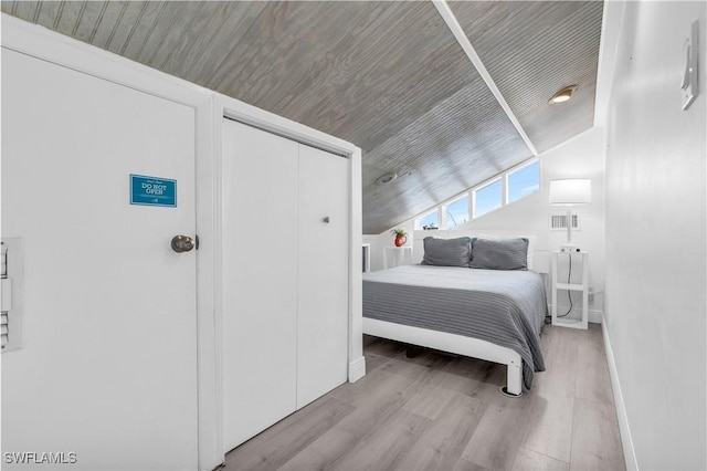 bedroom featuring vaulted ceiling, a closet, light wood-type flooring, and wooden ceiling