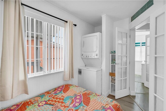 bedroom with stacked washer and clothes dryer and light wood-type flooring