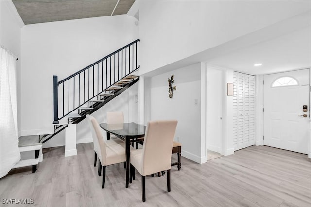 dining space with light wood finished floors, baseboards, and stairway