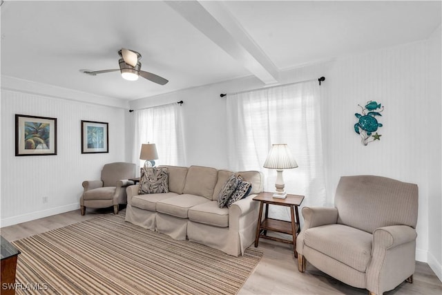 living room with beamed ceiling, light wood-type flooring, and ceiling fan