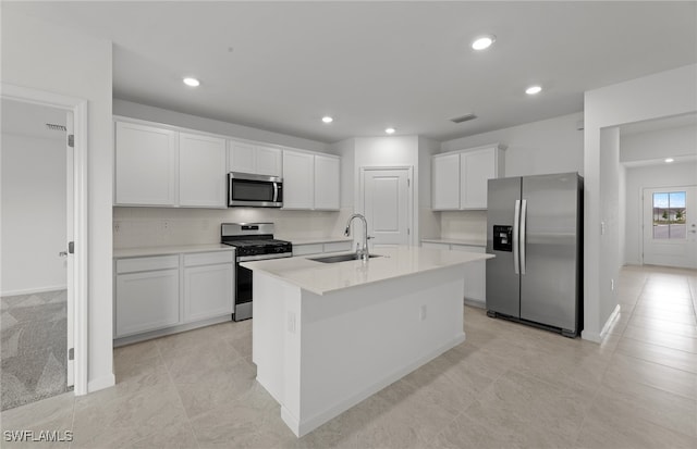 kitchen featuring stainless steel appliances, white cabinetry, light tile patterned floors, sink, and a kitchen island with sink