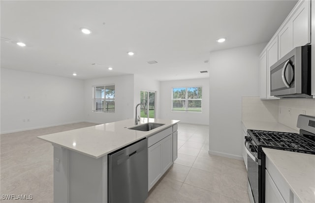 kitchen featuring an island with sink, white cabinets, sink, and appliances with stainless steel finishes