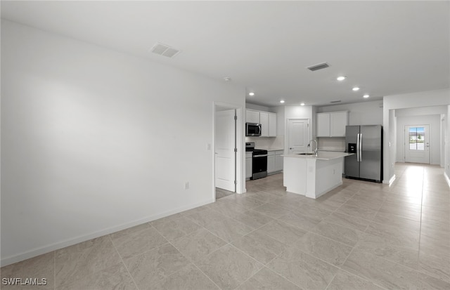 kitchen with stainless steel appliances, light tile patterned flooring, sink, an island with sink, and white cabinets