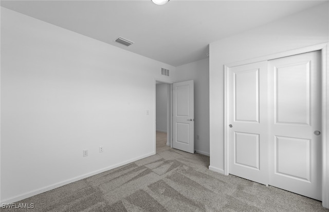 unfurnished bedroom with light carpet and a closet