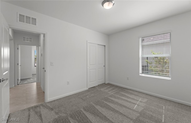 unfurnished bedroom featuring a closet and light colored carpet