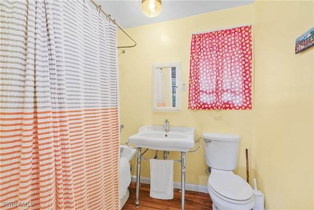 bathroom featuring a shower with curtain, hardwood / wood-style flooring, and toilet