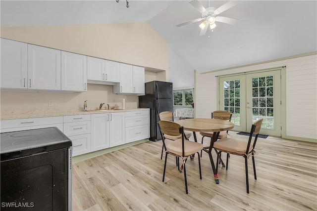 kitchen with range, black fridge, sink, light wood-type flooring, and white cabinetry