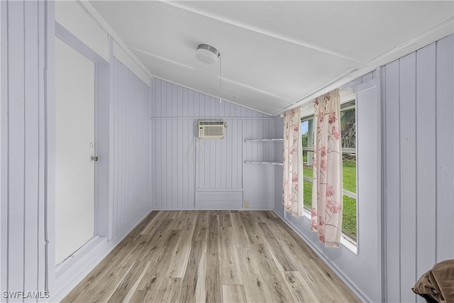 interior space featuring a wall unit AC, wood walls, vaulted ceiling, and light wood-type flooring