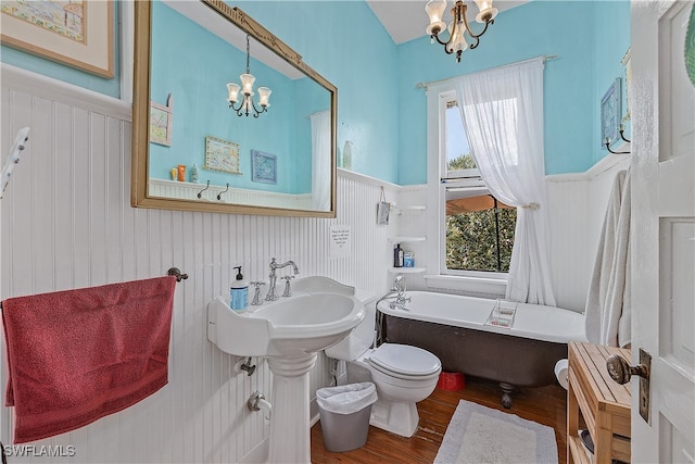 bathroom featuring hardwood / wood-style floors, a notable chandelier, a bathtub, and toilet