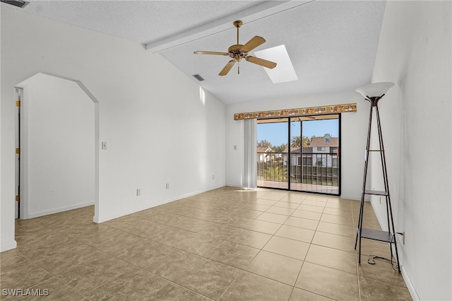 unfurnished room featuring ceiling fan, light tile patterned flooring, lofted ceiling with skylight, and a textured ceiling