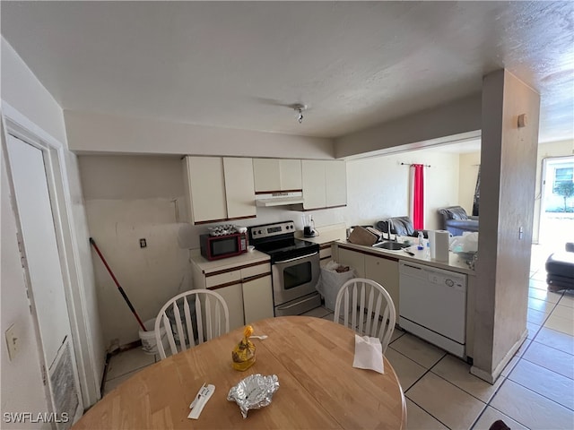 kitchen featuring stainless steel electric range, white dishwasher, sink, light tile patterned floors, and white cabinetry