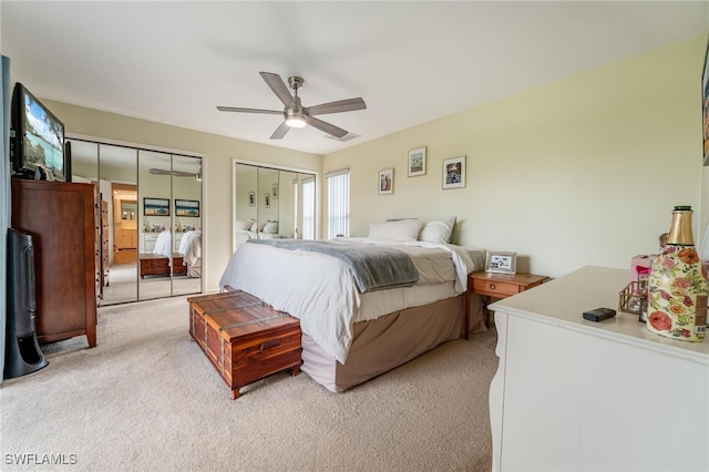 carpeted bedroom with ceiling fan and two closets