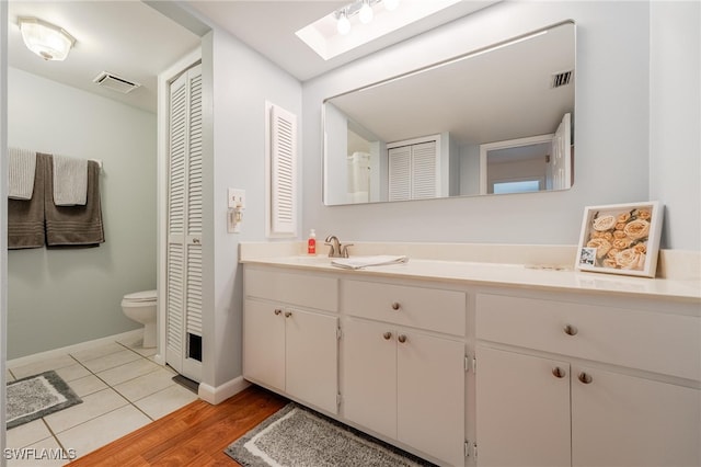 bathroom with vanity, toilet, wood-type flooring, and a skylight