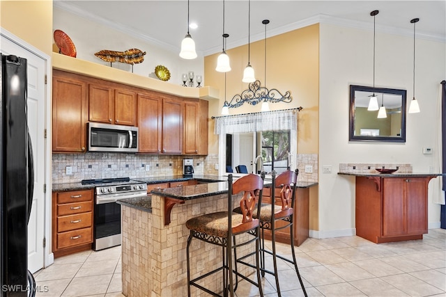 kitchen with decorative light fixtures, a kitchen bar, ornamental molding, and stainless steel appliances