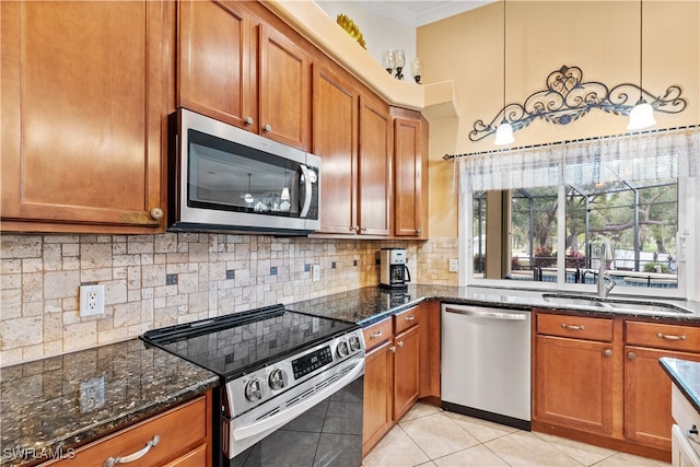 kitchen featuring backsplash, sink, dark stone countertops, appliances with stainless steel finishes, and decorative light fixtures