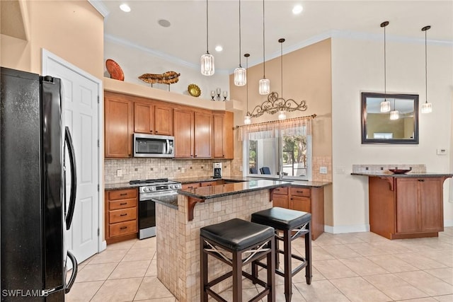 kitchen featuring brown cabinetry, decorative backsplash, stainless steel appliances, crown molding, and a kitchen bar