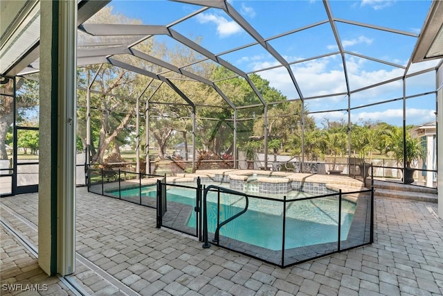 view of pool featuring a pool with connected hot tub, a patio area, and a lanai