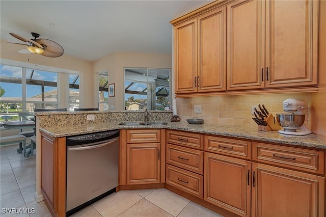 kitchen with stainless steel dishwasher, plenty of natural light, sink, and light stone counters