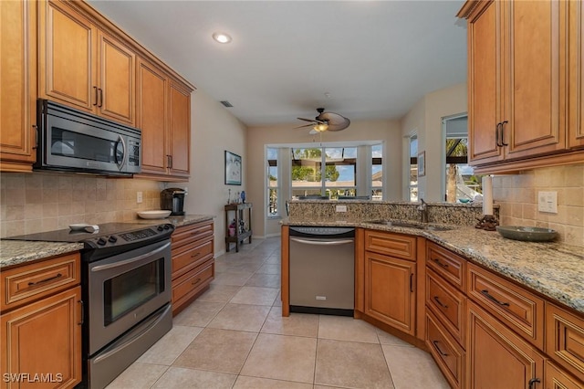 kitchen featuring light stone countertops, sink, stainless steel appliances, and light tile patterned flooring