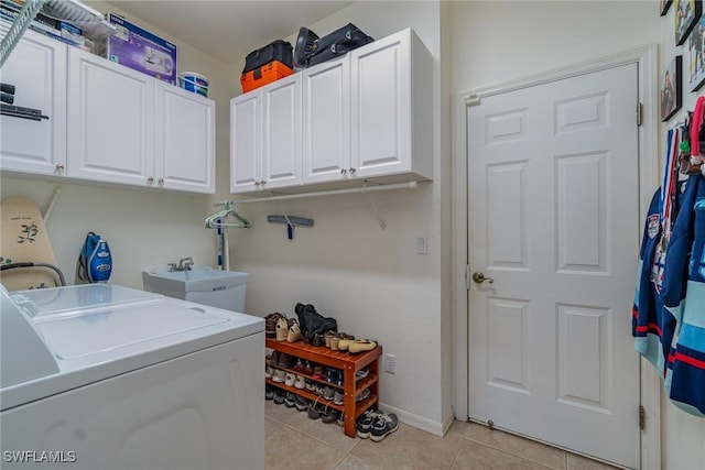 washroom with light tile patterned floors, washer and clothes dryer, sink, and cabinets