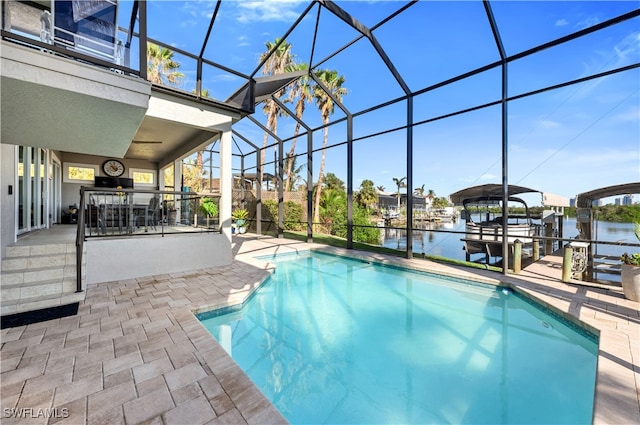 view of swimming pool with glass enclosure, a water view, and a patio