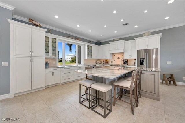 kitchen featuring a kitchen bar, white cabinets, high quality fridge, and a large island