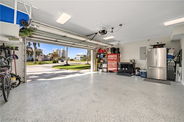 garage featuring a garage door opener, electric panel, and stainless steel refrigerator