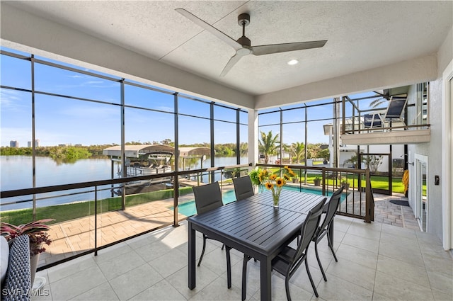 sunroom / solarium featuring a water view and ceiling fan