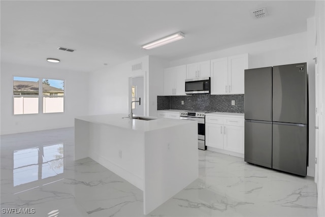 kitchen featuring tasteful backsplash, stainless steel appliances, sink, white cabinets, and a kitchen island with sink