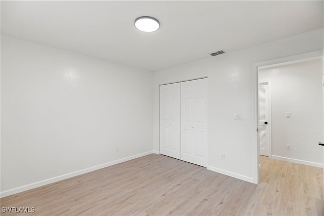 unfurnished bedroom with light wood-type flooring and a closet