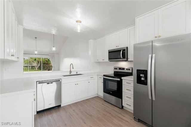 kitchen featuring white cabinetry, sink, appliances with stainless steel finishes, hanging light fixtures, and light hardwood / wood-style flooring