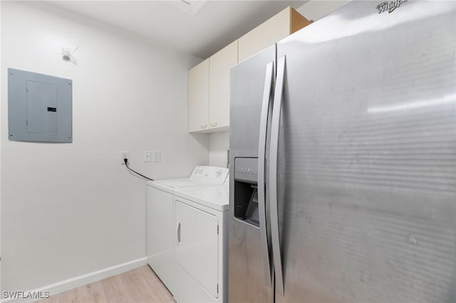 laundry room featuring electric panel, cabinets, washer and dryer, and light wood-type flooring