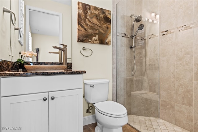 bathroom featuring vanity, tile patterned flooring, toilet, and a tile shower