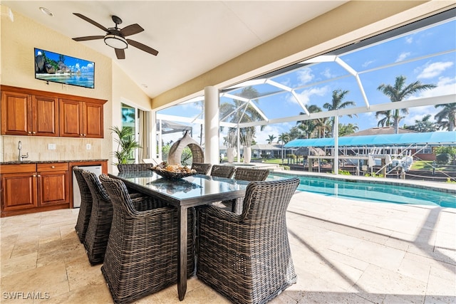 view of patio with ceiling fan, sink, and glass enclosure