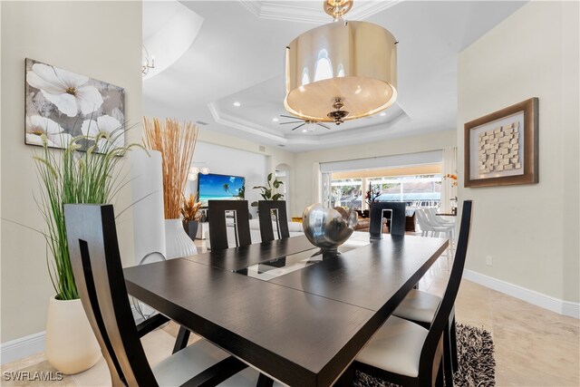 dining area with a raised ceiling, ornamental molding, and light tile patterned flooring