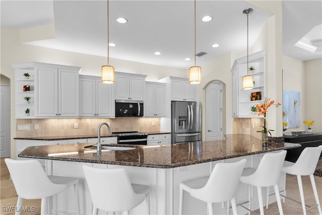 kitchen featuring sink, dark stone counters, pendant lighting, stainless steel appliances, and white cabinets