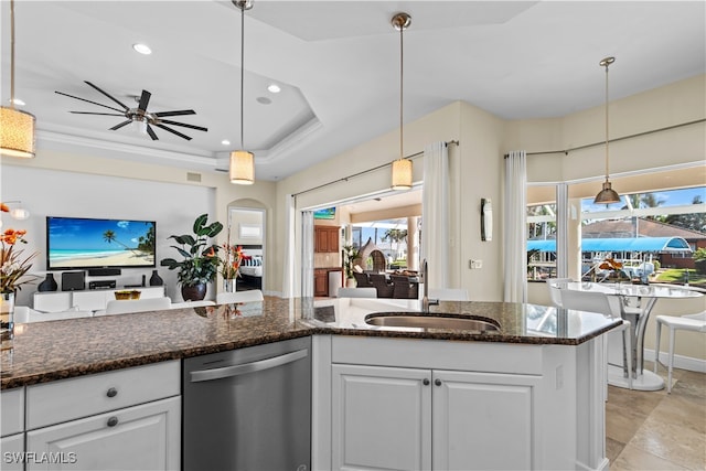 kitchen featuring stainless steel dishwasher, pendant lighting, a raised ceiling, white cabinetry, and sink