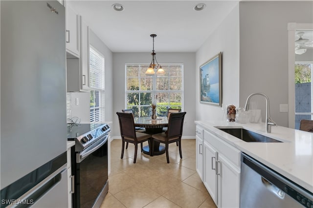 kitchen with light tile patterned flooring, stainless steel appliances, decorative light fixtures, sink, and white cabinets