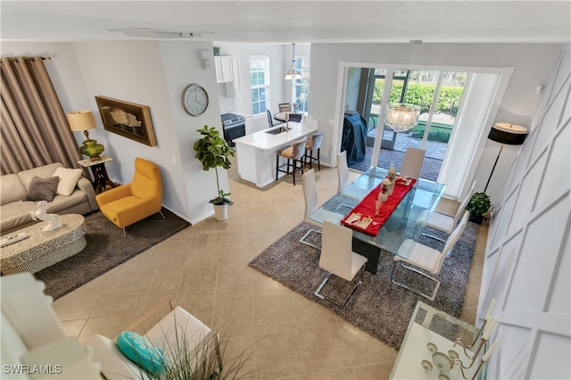 tiled living room with an inviting chandelier, vaulted ceiling, and a healthy amount of sunlight