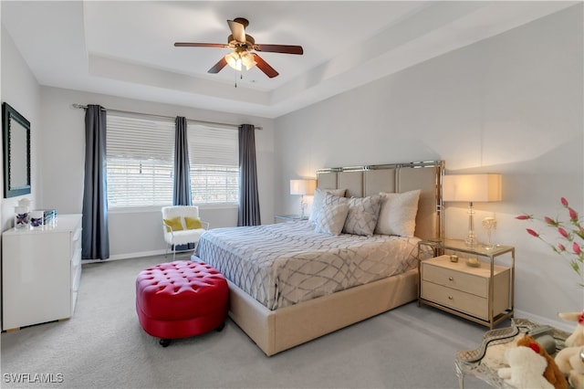 bedroom featuring light carpet, ceiling fan, and a raised ceiling