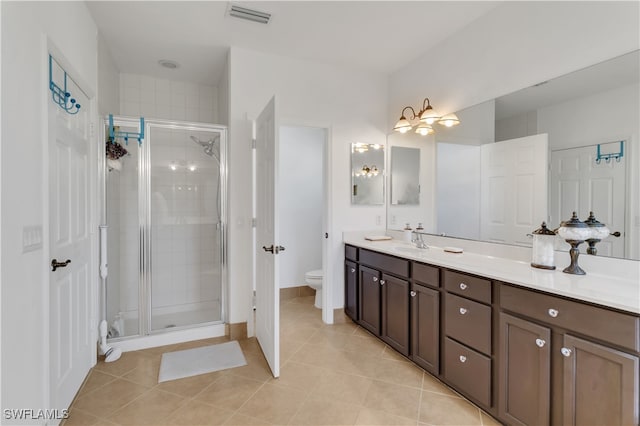 bathroom with toilet, vanity, tile patterned floors, and a shower with shower door