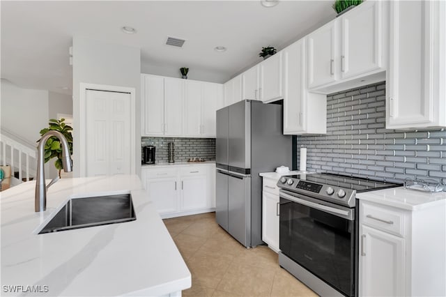 kitchen featuring light tile patterned flooring, stainless steel appliances, white cabinetry, backsplash, and sink