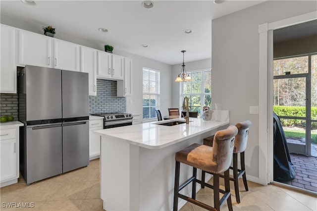 kitchen featuring stainless steel appliances, backsplash, hanging light fixtures, white cabinets, and kitchen peninsula