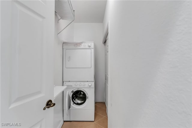 clothes washing area featuring light tile patterned floors and stacked washer and dryer