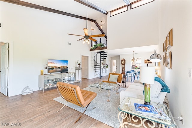 living room featuring light hardwood / wood-style flooring, a towering ceiling, ceiling fan, and beam ceiling