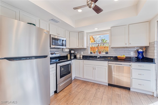 kitchen with white cabinets, sink, decorative backsplash, appliances with stainless steel finishes, and light wood-type flooring