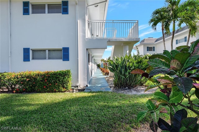 back of property with a yard and a balcony