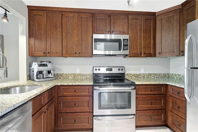 750 Mooring Line Dr Unit 105, Naples, FL 34102 - kitchen featuring stainless steel appliances, a sink, light stone counters, and rail lighting