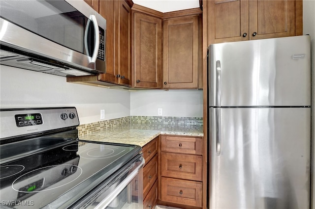 750 Mooring Line Dr Unit 105, Naples, FL 34102 - kitchen with stainless steel appliances, brown cabinets, and light stone countertops