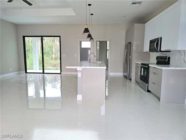 kitchen with stainless steel appliances, white cabinetry, sink, and decorative light fixtures